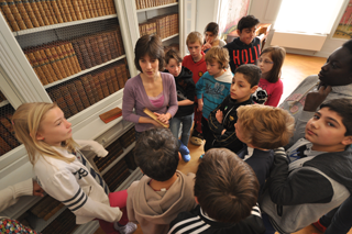 kinderen staan verzameld rond gids in de bibliotheek van de kasteel